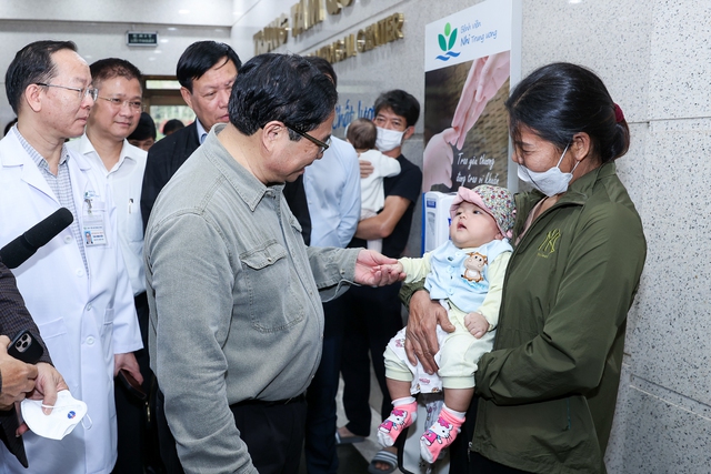 Thủ tướng hỏi thăm sức khỏe một trẻ đang khám tại Bệnh viện Nhi Trung ương trong thời điểm thời tiết chuyển mùa - Ảnh: VGP/Nhật Bắc