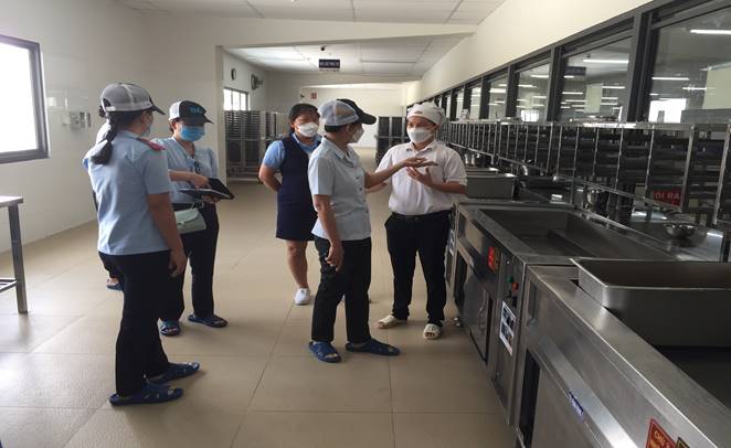 Đoàn kiểm tra hướng dẫn người đại diện của bếp ăn tập thể tuân thủ các quy định trong quá trình chế biến thức ăn