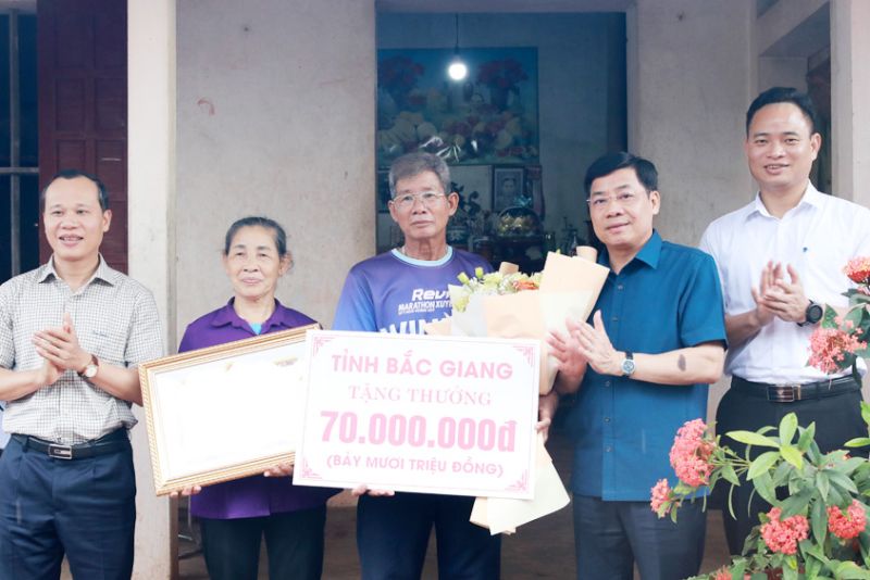 Ông Dương Văn Thái, Mai Sơn trao tiền thưởng và Bằng khen của Chủ tịch UBND tỉnh cho đại diện gia đình vận động viên Nguyễn Thị Oanh.