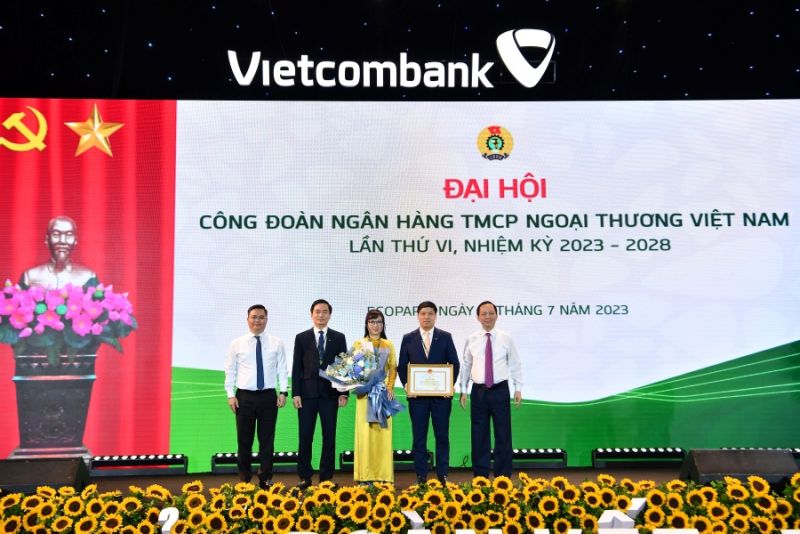 Ông Đào Minh Tú - Phó Bí thư Ban cán sự Đảng, Phó Thống đốc thường trực Ngân hàng Nhà nước Việt Nam, Ủy viên Ban Chấp hành Tổng Liên đoàn Lao động Việt Nam, Chủ tịch Công đoàn Ngân hàng Việt Nam (ngoài cùng bên phải) trao tặng Bằng khen của Thống đốc Ngân hàng Nhà nước và ông Nguyễn Thanh Tùng - Phó Bí thư Đảng ủy, Thành viên Hội đồng quản trị, Tổng Giám đốc Vietcombank (ngoài cùng bên trái) tặng hoa cho đại diện Công đoàn Vietcombank