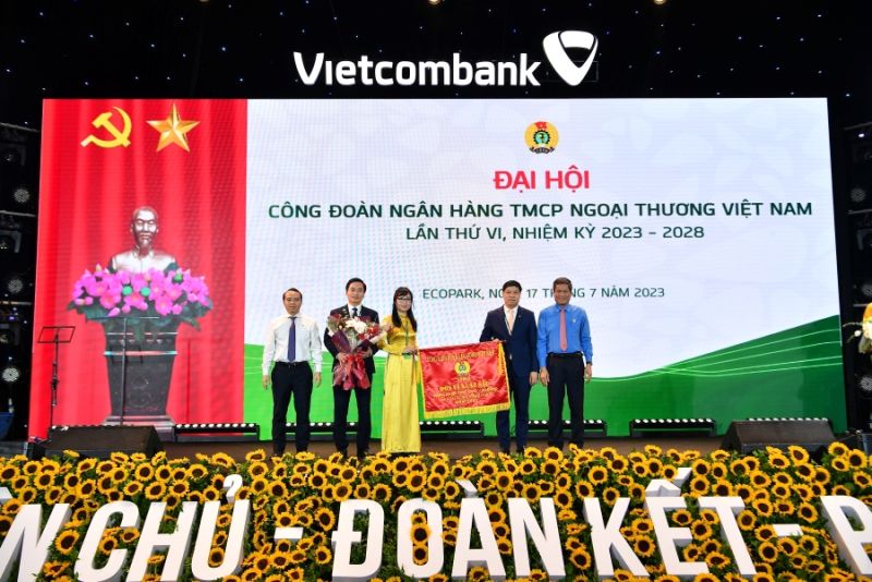 Ông Huỳnh Thanh Xuân – Phó Chủ tịch Tổng Liên đoàn Lao động Việt Nam (ngoài cùng bên phải) tặng Cờ Thi đua của Tổng Liên đoàn Lao động Việt Nam và ông Đỗ Việt Hùng – Phó Bí thư thường trực Đảng ủy Vietcombank (ngoài cùng bên trái) tặng hoa cho đại diện Công đoàn Vietcombank
