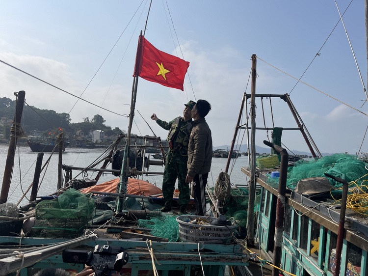Bộ đội Biên phòng tặng và cùng treo cờ Tổ quốc trên tàu cá đánh bắt xa bờ của ngư dân