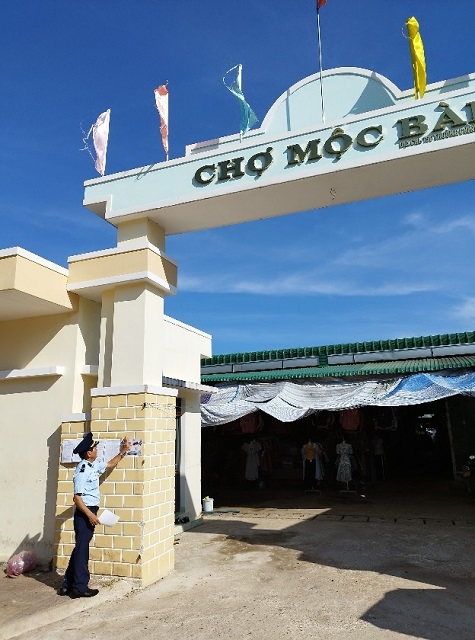 Lực lượng Đội QLTT số 1 thực hiện d&aacute;n &aacute;p-ph&iacute;ch tại chợ Mộc B&agrave;i. Ảnh: T-Lu&acirc;n.