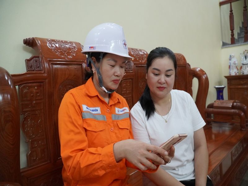 2 Công nhân Điện lực TP Uông Bí hướng dẫn khách hàng thanh toán tiền điện qua App chăm sóc khách hàng của Tổng công ty Điện lực miền Bắc