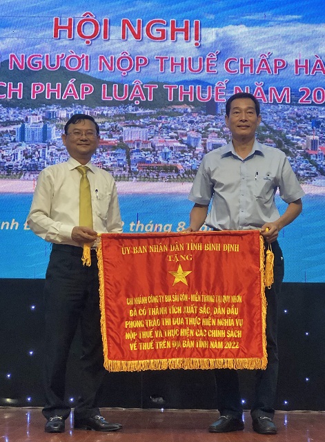 Ông Nguyễn Tự Công Hoàng (bên trái) trao tặng Cờ Thi đua của UBND tỉnh Bình Định cho đại diện Chi nhánh Công ty CP Bia Sài Gòn - miền Trung tại Quy Nhơn.