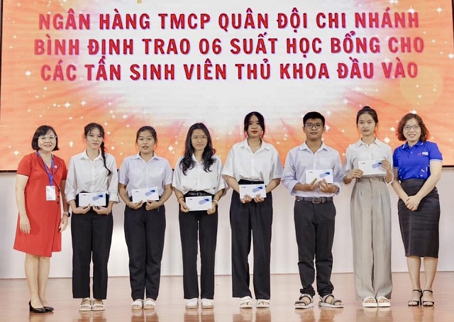 Bà Đặng Thị Vương Trang (bìa phải) và đại diện lãnh đạo Khoa Kinh tế và Kế toán trao học bổng cho 6 tân sinh viên.
