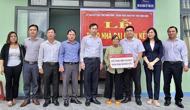 Ông Đồng Ngọc Ba (thứ 05 từ phải qua) và ông Nguyễn Hoàng Hải (thứ 03 từ phải qua) trao tiền hỗ trợ xây dựng nhà Đại đoàn kết cho bà Đặng Thị Bốn.