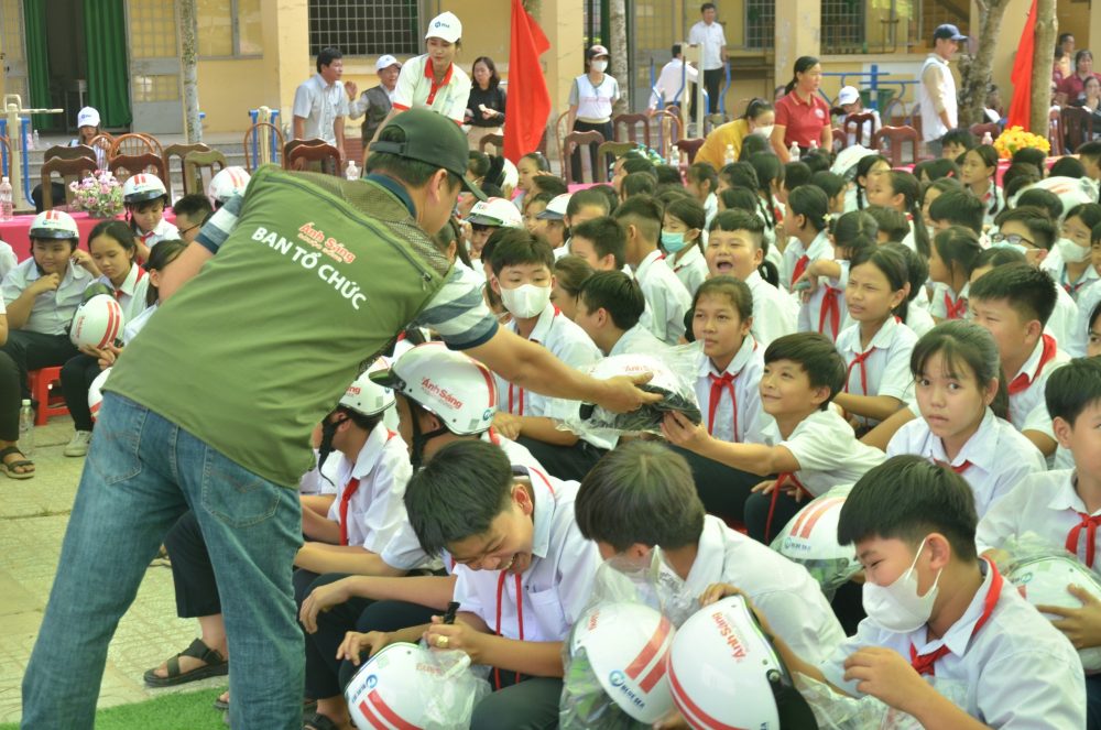Các thành viên đoàn “Ánh sáng học đường” tặng mũ bảo hiểm cho các em học sinh