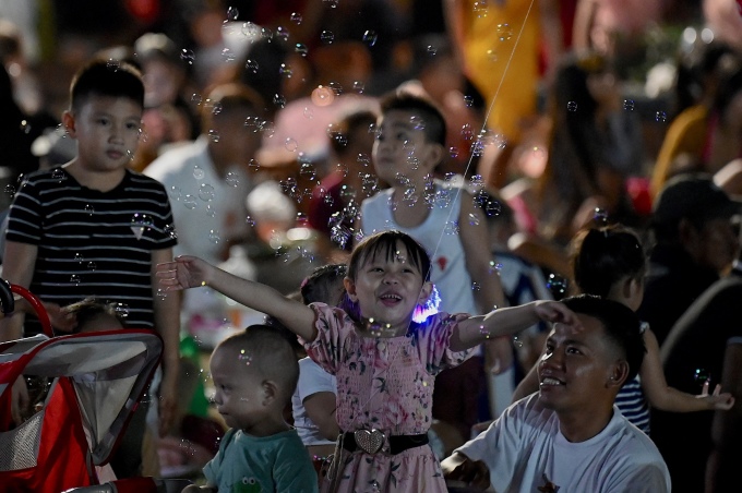 Bé gái thích thú với bong bóng xà phòng trong lúc chờ xem pháo hoa ở công viên Rizal, Manila. Ảnh: AFP