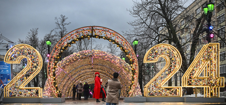 Người đi bộ tạo dáng trước trang trí năm mới 2024 ở trung tâm Matxcơva, Nga, ngày 31/12 - Ảnh: Reuters