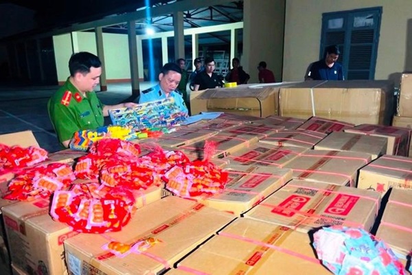 Lực lượng chức năng đang tiến hành kiểm tra lô hàng gồm chả bò chay, kẹo, đồ chơi trẻ em. ảnh( Thanh Tuấn)