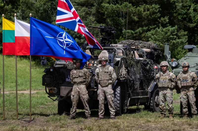 Binh sĩ Anh và Mỹ bên cạnh cờ NATO (Ảnh: Sputnik).