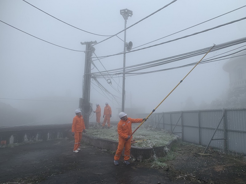 Công nhân Điện lực Lộc Bình gạt các tảng băng dày bám vào đường dây