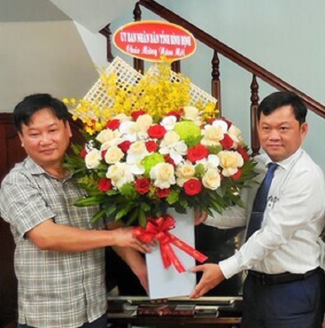 Ông Trần Kim Kha (bên phải) tặng hoa chúc Tết đại diện Báo Lao Động tại Bình Định. Ảnh: V.Lực