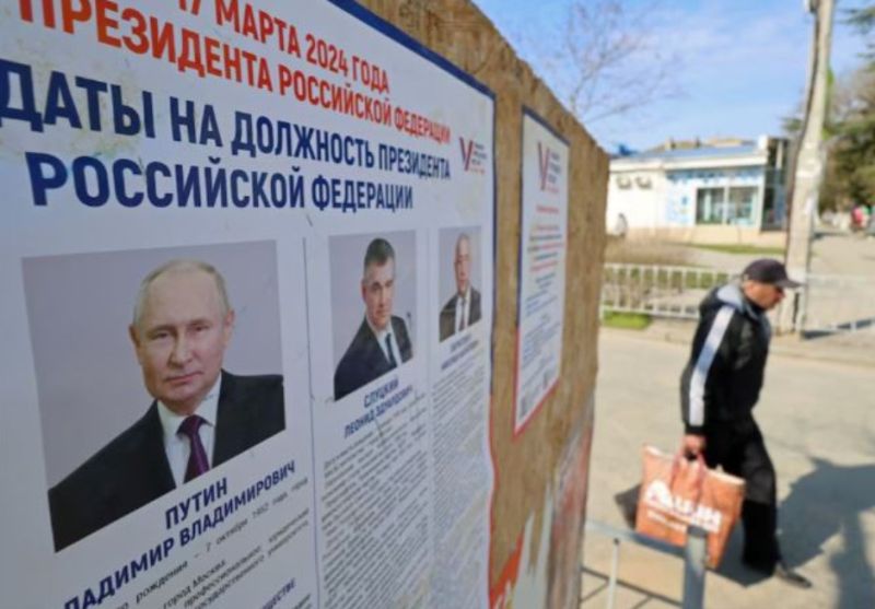 Một người đàn ông đi ngang qua bảng thông tin có chân dung của các ứng cử viên tổng thống Nga trong cuộc bầu cử sắp tới ở Yevpatoriya, Crimea ngày 8/3/2024.