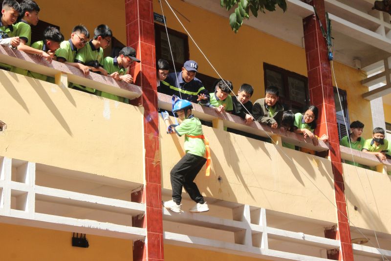 Các em học sinh thực hành thoát hiểm bằng thang dây