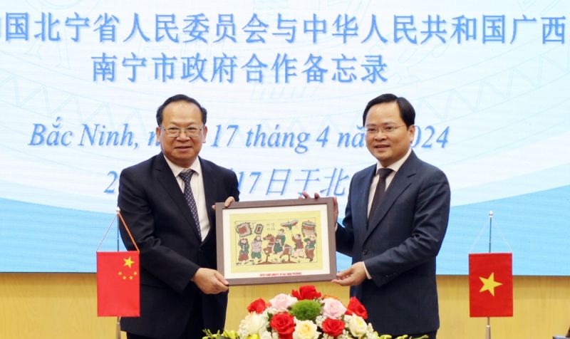 Bí thư Tỉnh ủy Nguyễn Anh Tuấn (bên phải) trao tặng tranh dân gian Đông Hồ cho Bí thư Thành ủy Nam Ninh Nông Sinh Văn.