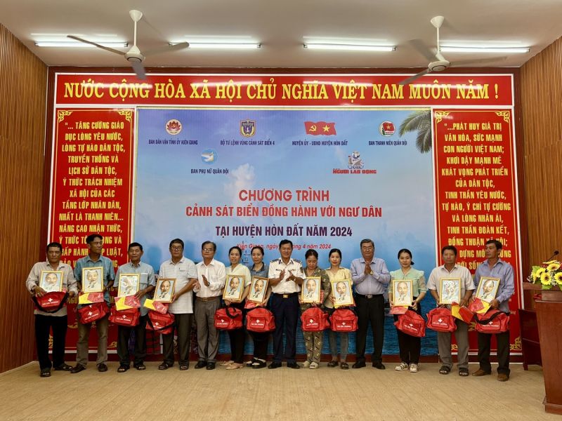 Đại tá Nguyễn Thái Dương - Phó Chính ủy BTL Vùng Cảnh sát biển 4 tặng cờ Tổ quốc, ảnh Bác Hồ, túi thuốc y tế cho bà con ngư dân.
