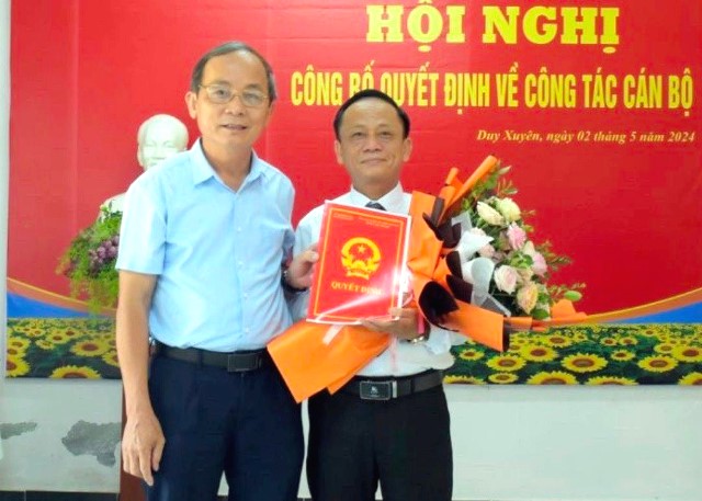 Ông Phan Xuân Cảnh, Chủ tịch UBND huyện Duy Xuyên, trao quyết định và tặng hoa chúc mừng ông Nguyễn Công Khiết