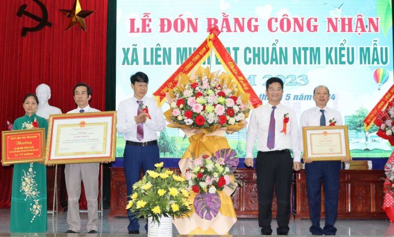 Phó Chủ tịch Thường trực UBND tỉnh Nam Định Trần Anh Dũng trao Bằng công nhận xã nông thôn mới kiểu mẫu và tặng hoa chúc mừng xã Liên Minh