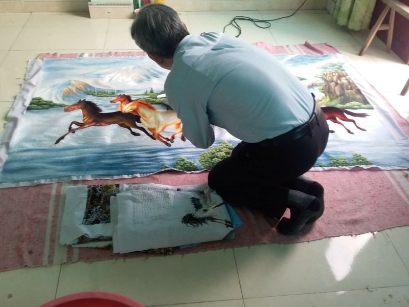 Nghệ nhân Nguyễn Cao Bính tỉ mỉ hoàn thiện bức trức thêu trước khi đóng khung