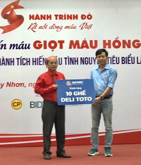 Đại diện Công ty TNHH Sản xuất, Thương mại, Dịch vụ Qui Phúc (bên trái) trao bảng tượng trưng tài trợ 10 ghế phục vụ cho người tham gia HMTN.