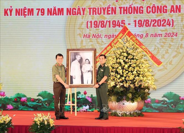 Đại tướng, Bộ trưởng Bộ Quốc phòng Phan Văn Giang, thay mặt Quân ủy Trung ương, Bộ Quốc phòng trao tặng bức ảnh Bác Hồ cho Thượng tướng, Bộ trưởng Bộ Công an Lương Tam Quang, thay mặt Đảng ủy Công an Trung ương, Bộ Công an. Ảnh: Trí Dũng/TTXVN