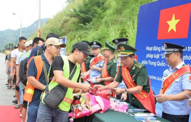 Lực lượng chức năng Việt Nam và Trung Quốc phát tờ rơi tuyên truyền cho người dân qua lại khu vực cửa khẩu