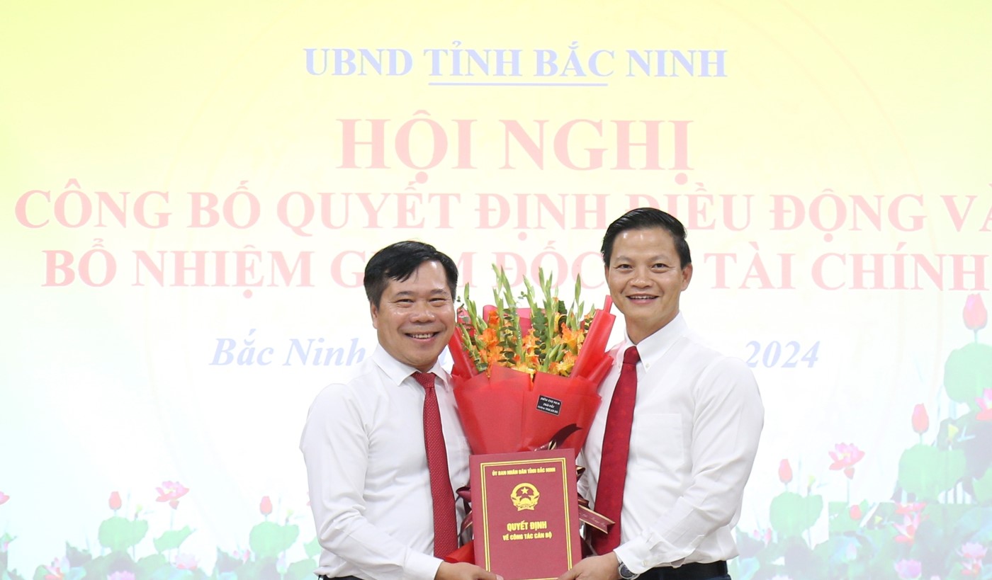 Chủ tịch UBND tỉnh Vương Quốc Tuấn (bên phải) trao Quyết định và tặng hoa chúc mừng tân Giám đốc Sở Tài chính Nguyễn Xuân Đương.