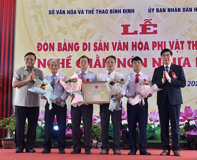 Các ông Lê Kim Toàn (bìa trái) và Lâm Hải Giang (bìa phải) trao Bằng di sản văn hóa phi vật thể quốc gia “Nghề chằm nón ngựa Phú Gia” cho lãnh đạo huyện Phù Cát, xã Cát Tường và đại diện làng nghề chằm nón ngựa Phú Gia nhận Ảnh: Viết Hiền