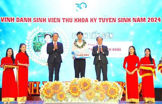 Phó Bí thư Thường trực Thành ủy Nguyễn Đình Vĩnh (bên trái) và Giám đốc Đại học Đà Nẵng Nguyễn Ngọc Vũ (bên phải) trao tặng thưởng cho thủ khoa đầu vào Trường Đại học Bách khoa, Đại học Đà Nẵng mùa tuyển sinh năm học 2024-2025.