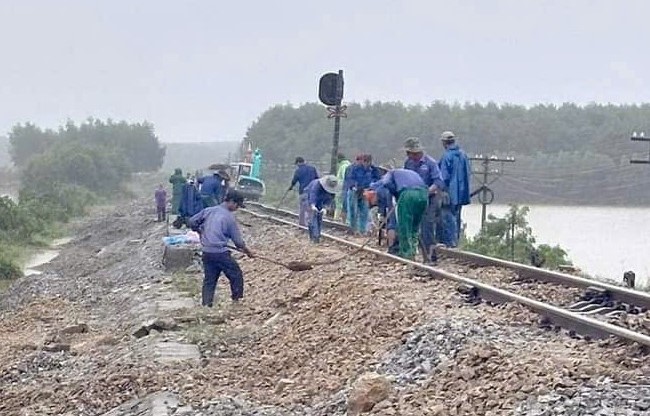 Các công nhân và phương tiện máy móc triển khai khắc phục lại nền đá bị nước lũ cuốn trôi.