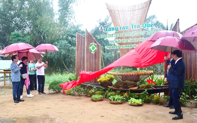 Đại biểu thực hiện nghi thức kéo băng vinh danh thương hiệu làng rau Trà Quế là làng du lịch tốt nhất năm 2024