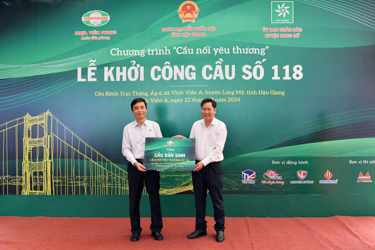 Ông Trần Ngọc Bảo - Thành viên HĐQT, Phó TGĐ Công ty CP Nhựa Thiếu niên Tiền Phong trao tặng biển Cầu nối yêu thương số 118 cho ông Nguyễn Vũ Trường - Chủ tịch UBND huyện Long Mỹ.