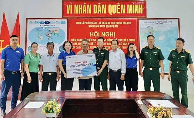 Đại diện Chi nhánh MB Bình Định (thứ 4 từ trái qua) phối hợp với Lữ đoàn 88 - Binh chủng hóa học trao tiền hỗ trợ xây dựng “Nhà Đại đoàn kết” cho một hộ gia đình ở xã Phước Thành, huyện Tuy Phước, tỉnh Bình Định. Ảnh: Thương Huyền