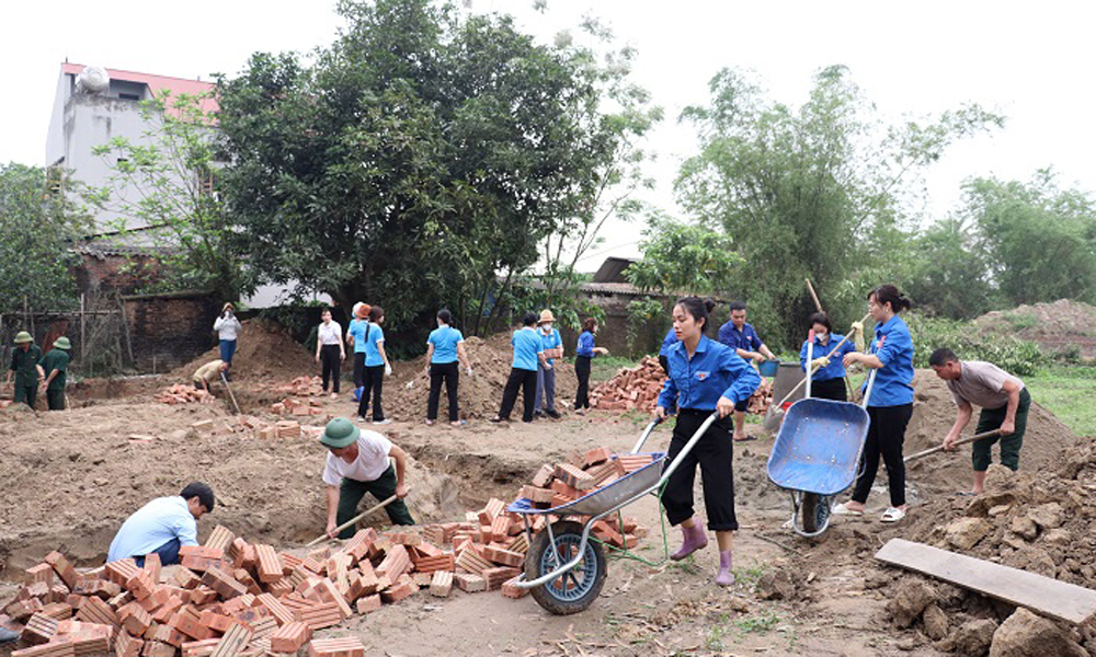 Đoàn viên, hội viên và nhân dân giúp đỡ bằng ngày công lao động để xây dựng nhà cho người nghèo.