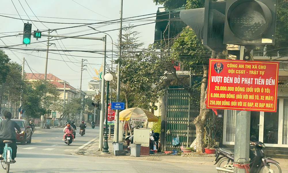 Biển thông báo các mức phạt đối với lỗi vượt đèn đỏ treo tại ngã tư giao giữa đường Trần Phú và đường Lê Duẩn, thị xã Chũ.