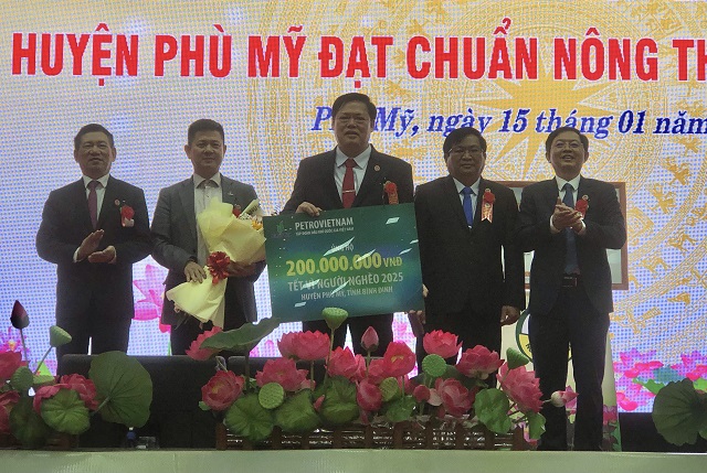 Đại diện Tập đoàn Xăng dầu Việt Nam (thứ 2 từ trái qua) trao bảng tượng trưng 200 triệu đồng ủng hộ các hộ nghèo ở huyện Phù Mỹ. Ảnh: VH