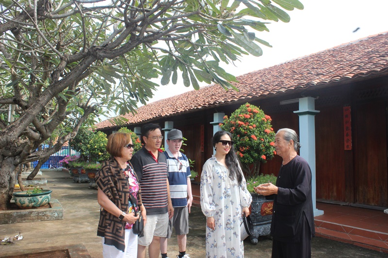 Chú Nguyễn Văn Lượng, một tín đồ Đạo Ông Trần giới thiệu về di tích Nhà Lớn với đoàn khách gia đình chị Nguyễn Thu Thủy đến từ Biên Hòa, Đồng Nai.