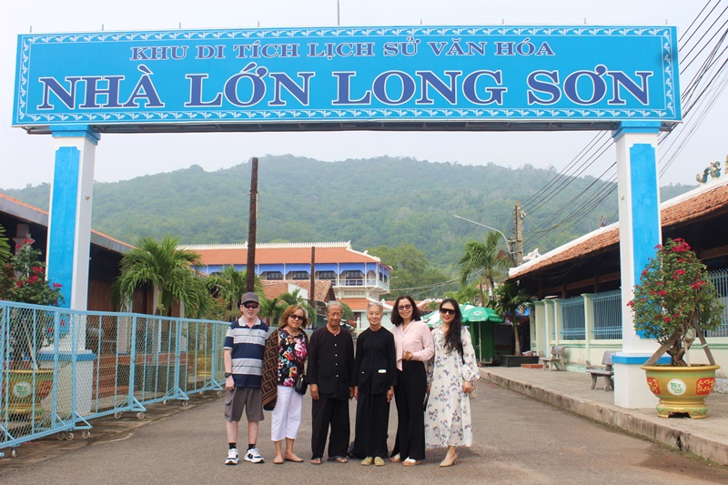 Bà Lê Thị Kiềm, ông Nguyễn Văn Lượng chụp hình lưu niệm cùng tác giả và đoàn khách tại cổng chính dẫn vào quần thể di tích Nhà Lớn Long Sơn