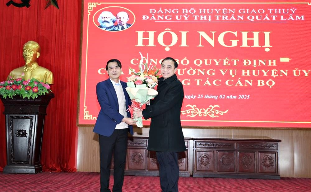 Đồng chí Nguyễn Xuân Đôi - Phó Bí thư Đảng ủy, Chủ tịch UBND thị trấn Quất Lâm tặng hoa chúc mừng đồng chí Tân Bí thư Đảng ủy