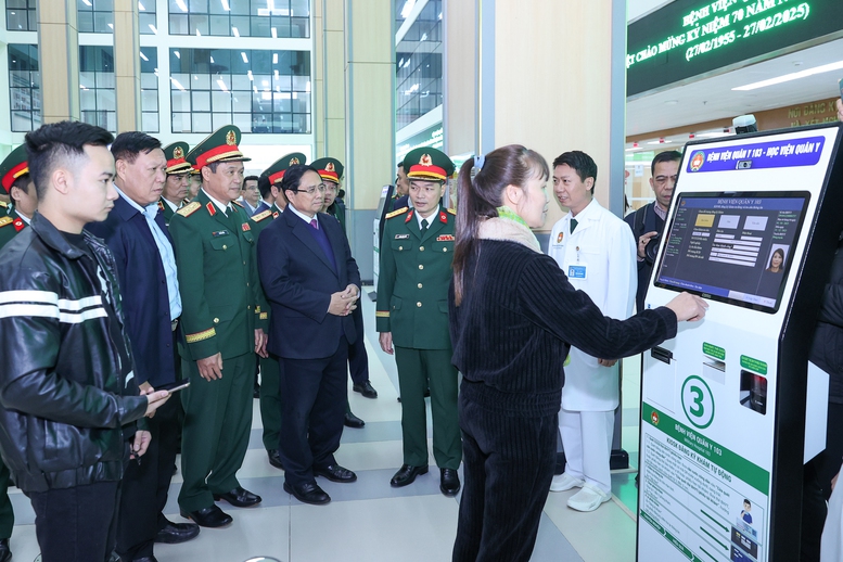 Thủ tướng nghe giới thiệu về hệ thống thực hiện thủ tục tiếp đón bệnh nhân tự động tại Bệnh viện 103 - Ảnh: VGP/Nhật Bắc