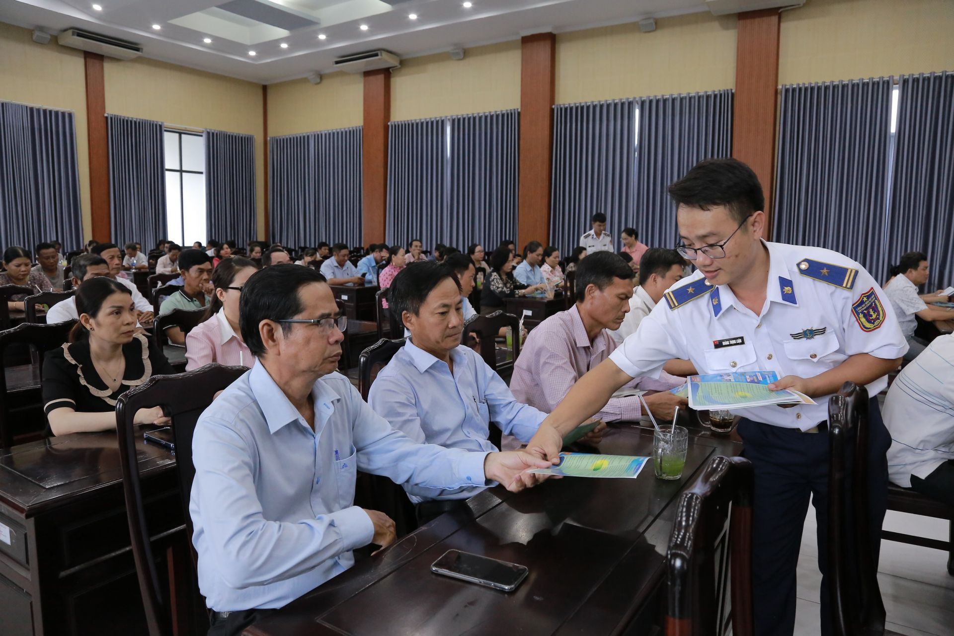 Cán bộ Bộ Tư lệnh Vùng Cảnh sát biển 4 phát tờ rơi tuyên truyền cho bà con ngư dân tham dự Hội nghị