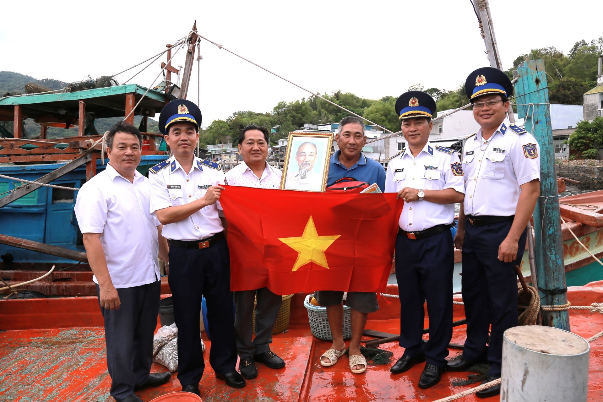 Cán bộ Bộ Tư lệnh Vùng Cảnh sát biển 4 và đại diện lãnh đạo địa phương tặng cờ Tổ quốc, ảnh Bác Hồ và túi thuốc y tế cho bà con ngư dân.