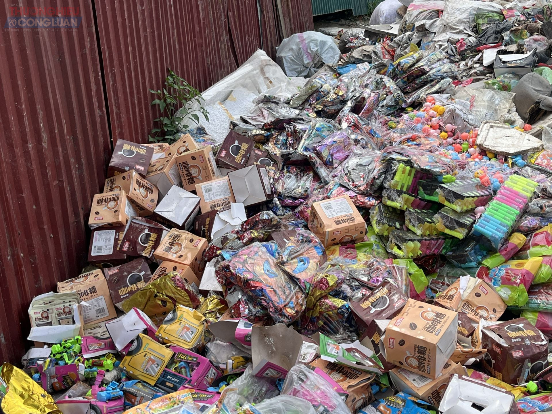 Hàng trăm bao tải, thùng carton chứa đầy bánh kẹo, nước giải khát bị vứt la liệt, trải dài cả trăm mét vuông. Nhiều sản phẩm đã biến dạng, đổi màu do tiếp xúc lâu với nắng nóng.