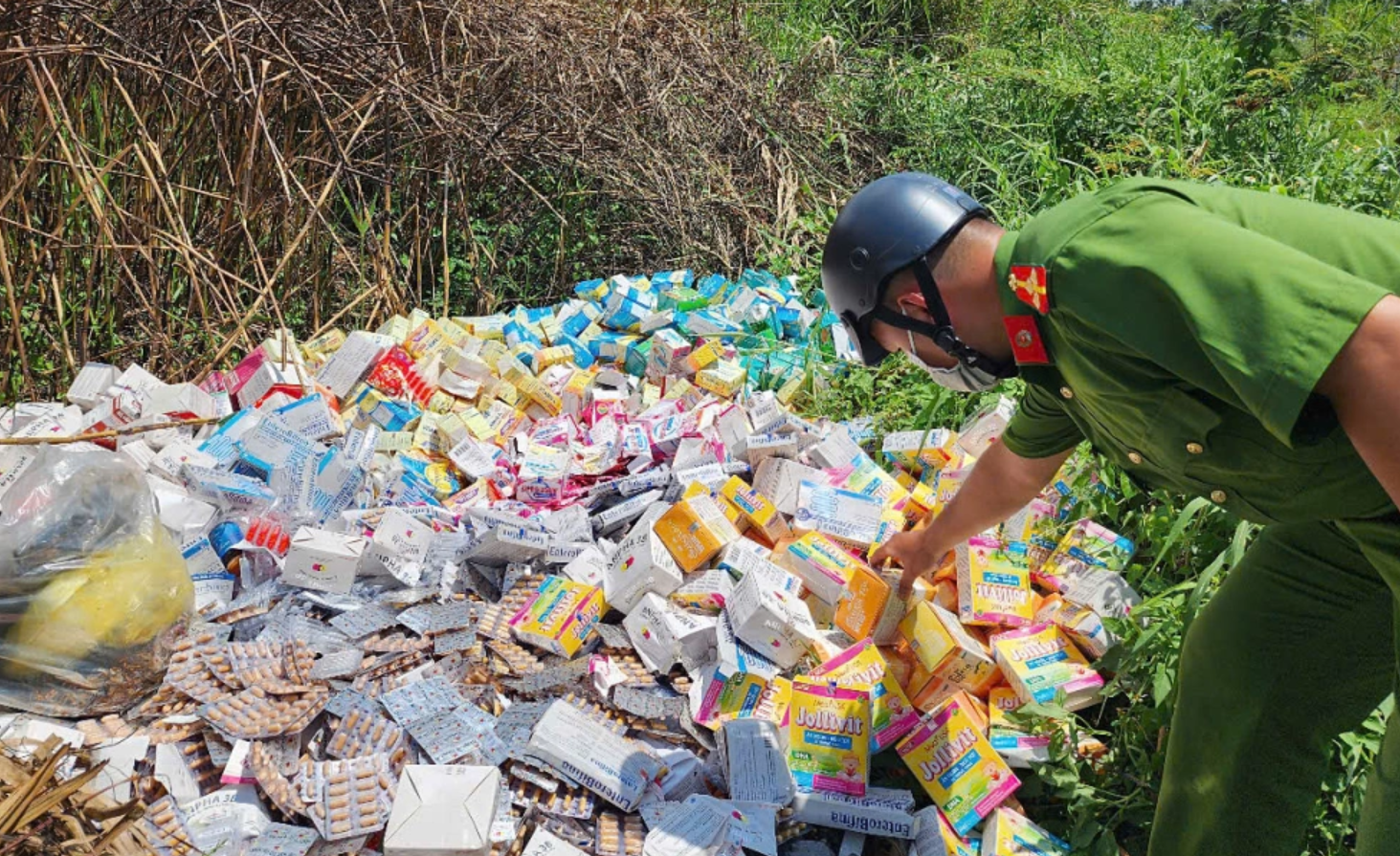 Cảnh sát kiểm tra các hộp thực phẩm chức năng bị bỏ ở bãi đất trống dọc đường Nguyễn Văn Linh, huyện Bình Chánh, trưa 6/6. Ảnh: Đình Văn