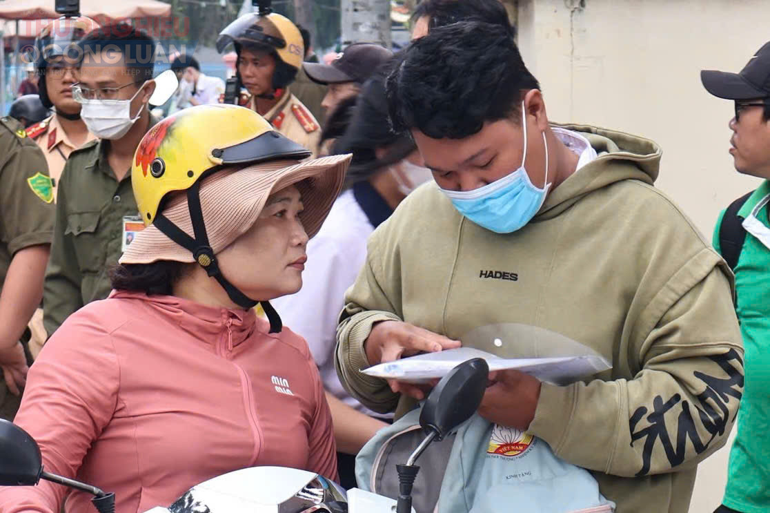 Phụ huynh hỗ trợ con em kiểm tra giấy tờ trước khi vào phòng thi. (Ảnh: Mai Dung)