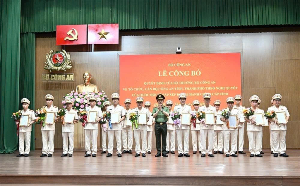 Bộ trưởng Lương Tam Quang trao Quyết định và tặng hoa chúc mừng các giám đốc công an địa phương sau sáp nhập. (Ảnh: Bộ Công an)