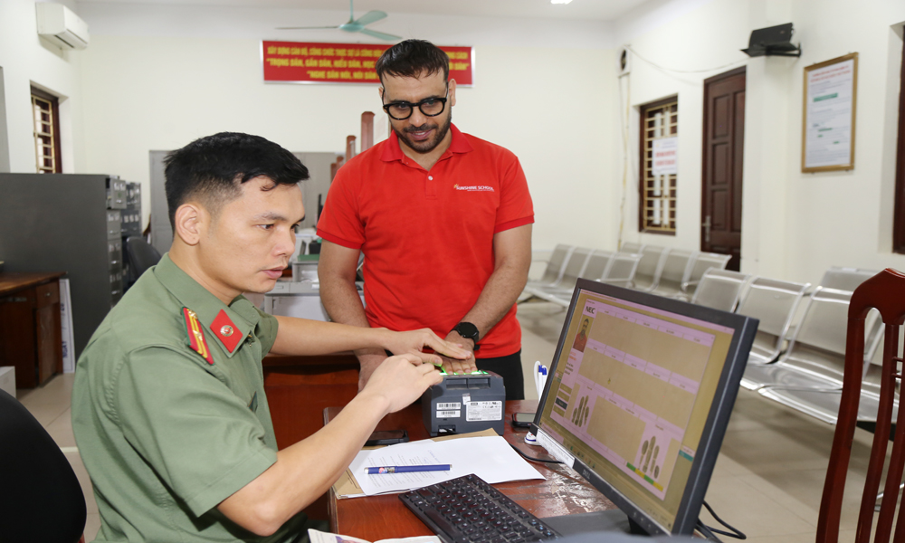 Cán bộ Phòng Quản lý xuất nhập cảnh (Cơ sở 2, phường Kinh Bắc) hướng dẫn người nước ngoài kiểm tra lại thông tin cá nhân.