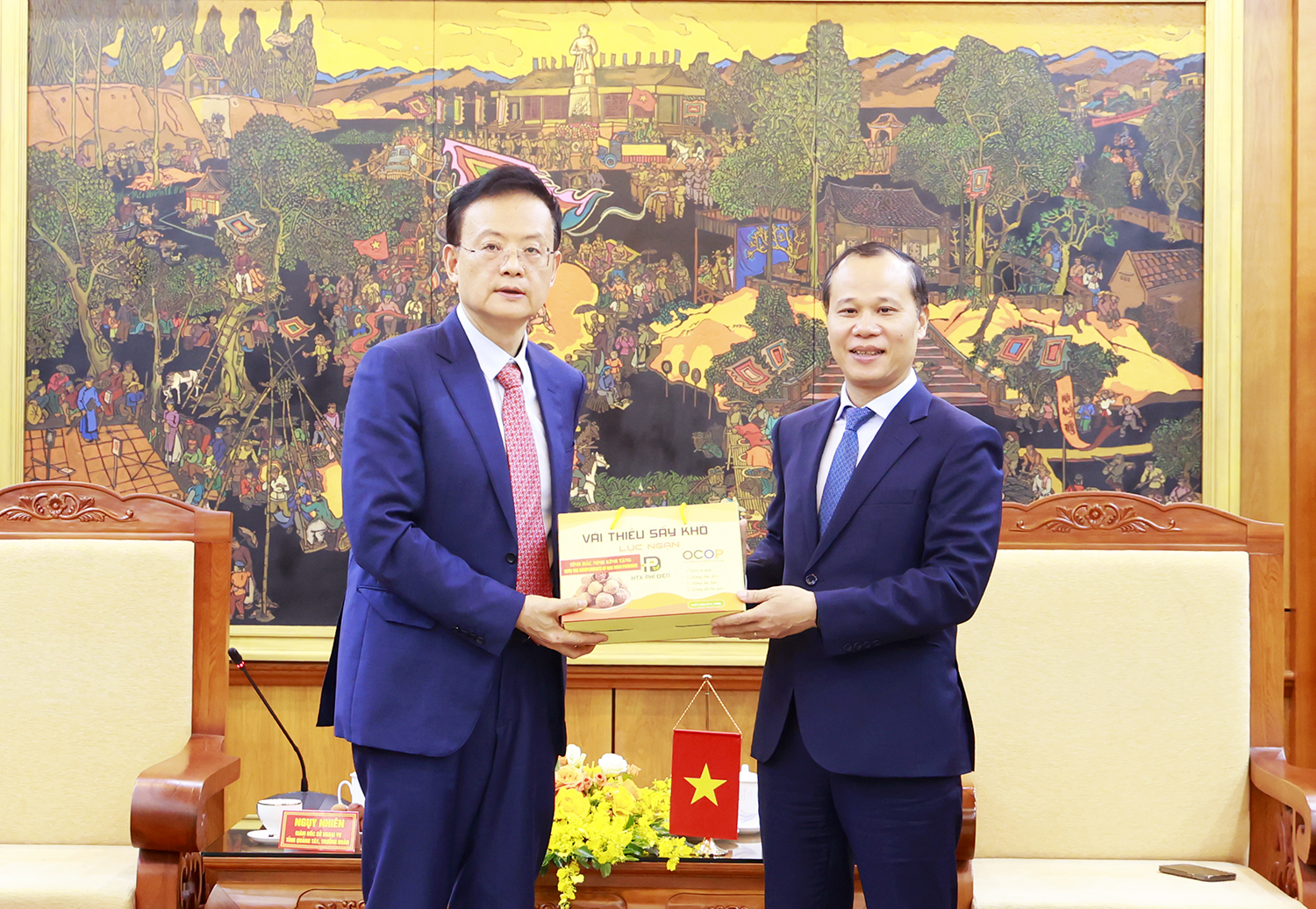 Phó Chủ tịch Thường trực UBND tỉnh Mai Sơn tặng sản phẩm nông sản địa phương (vải thiều sấy khô) cho ông Ngụy Nhiên, Giám đốc Sở Ngoại vụ Khu tự trị dân tộc Choang Quảng Tây, Trung Quốc